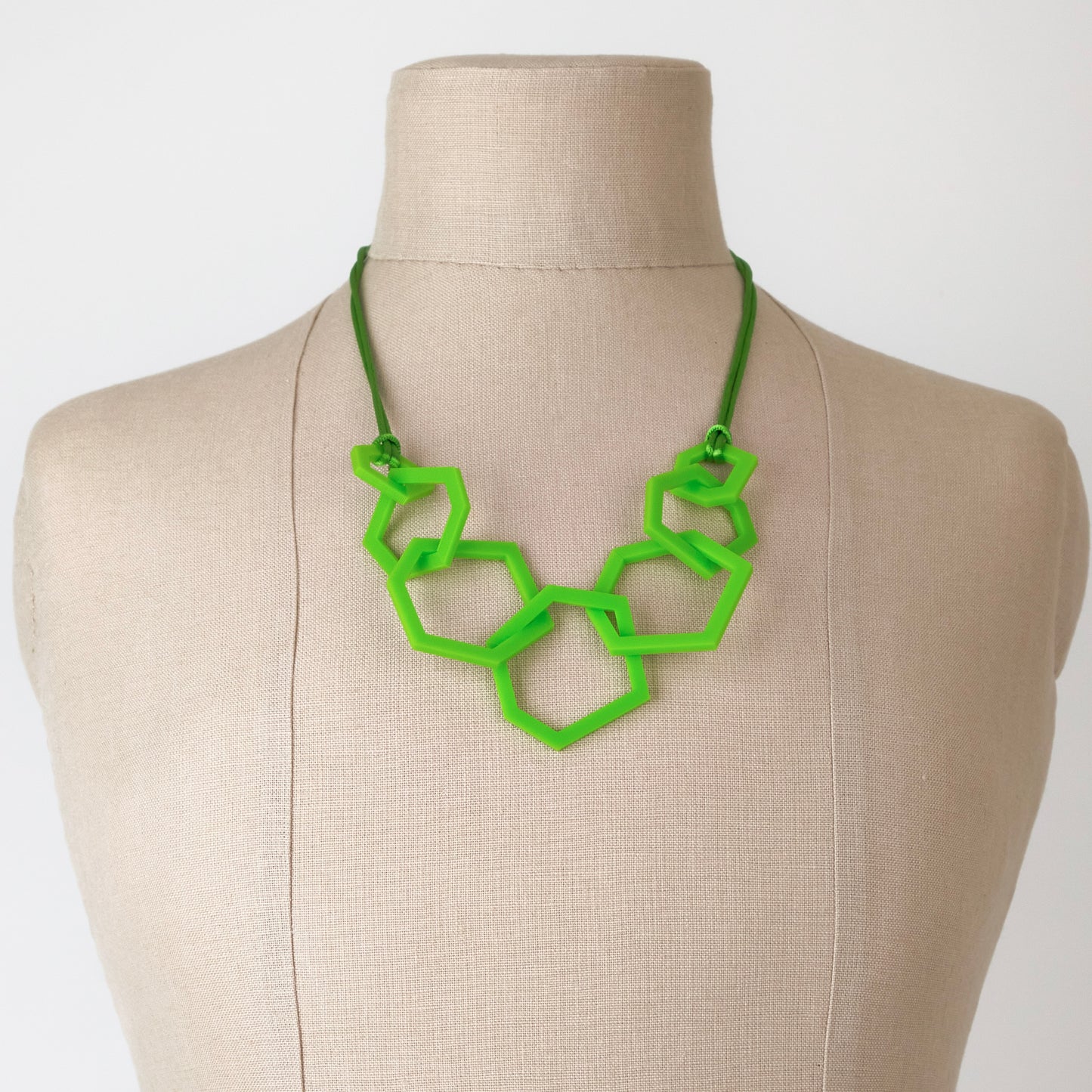 Lime Green geometric acrylic necklace on a mannequin bust against a white background