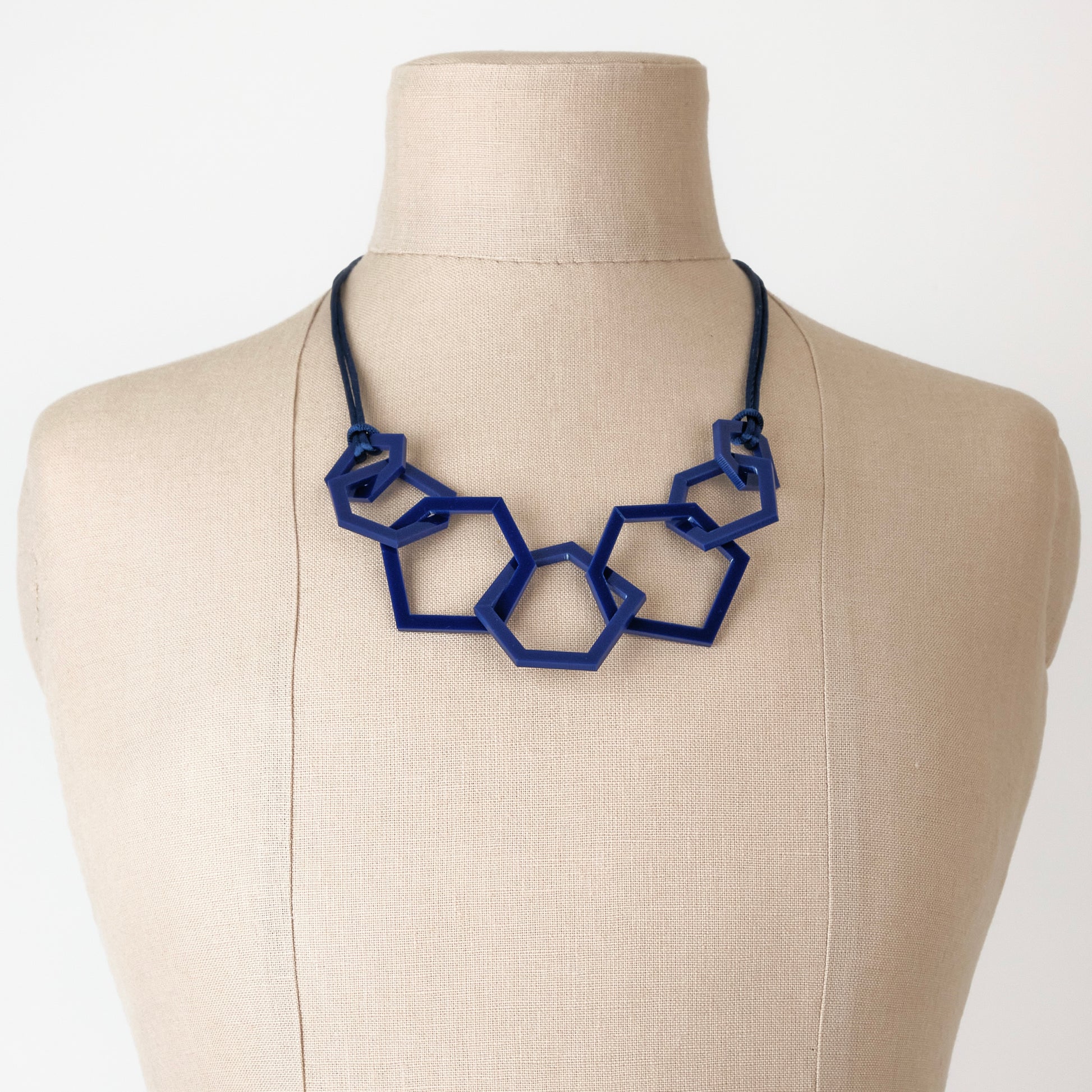 Navy Blue geometric necklace on a mannequin with a white background