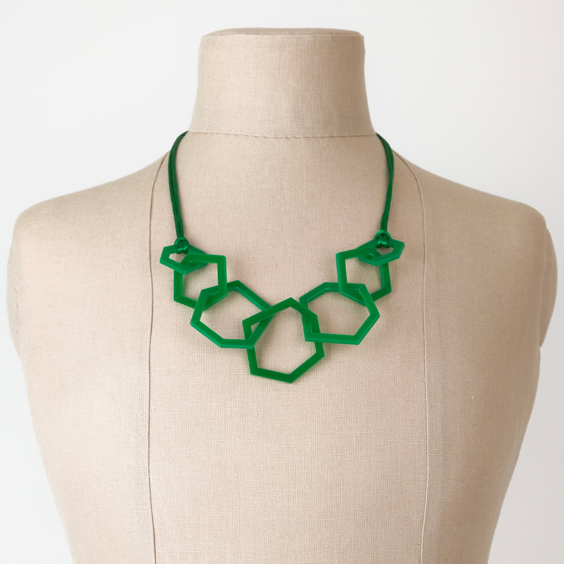 Emerald Green geometric necklace on a mannequin bust against a white background