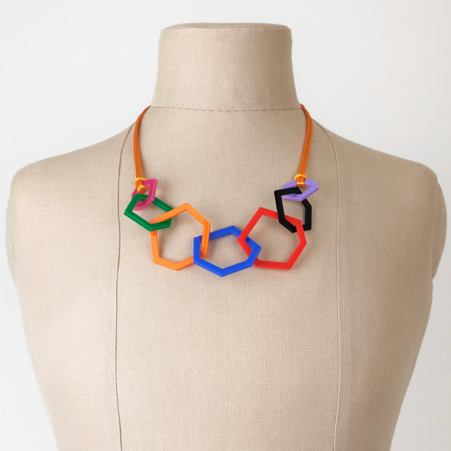 Colorful geometric necklace on a mannequin bust against a plain background