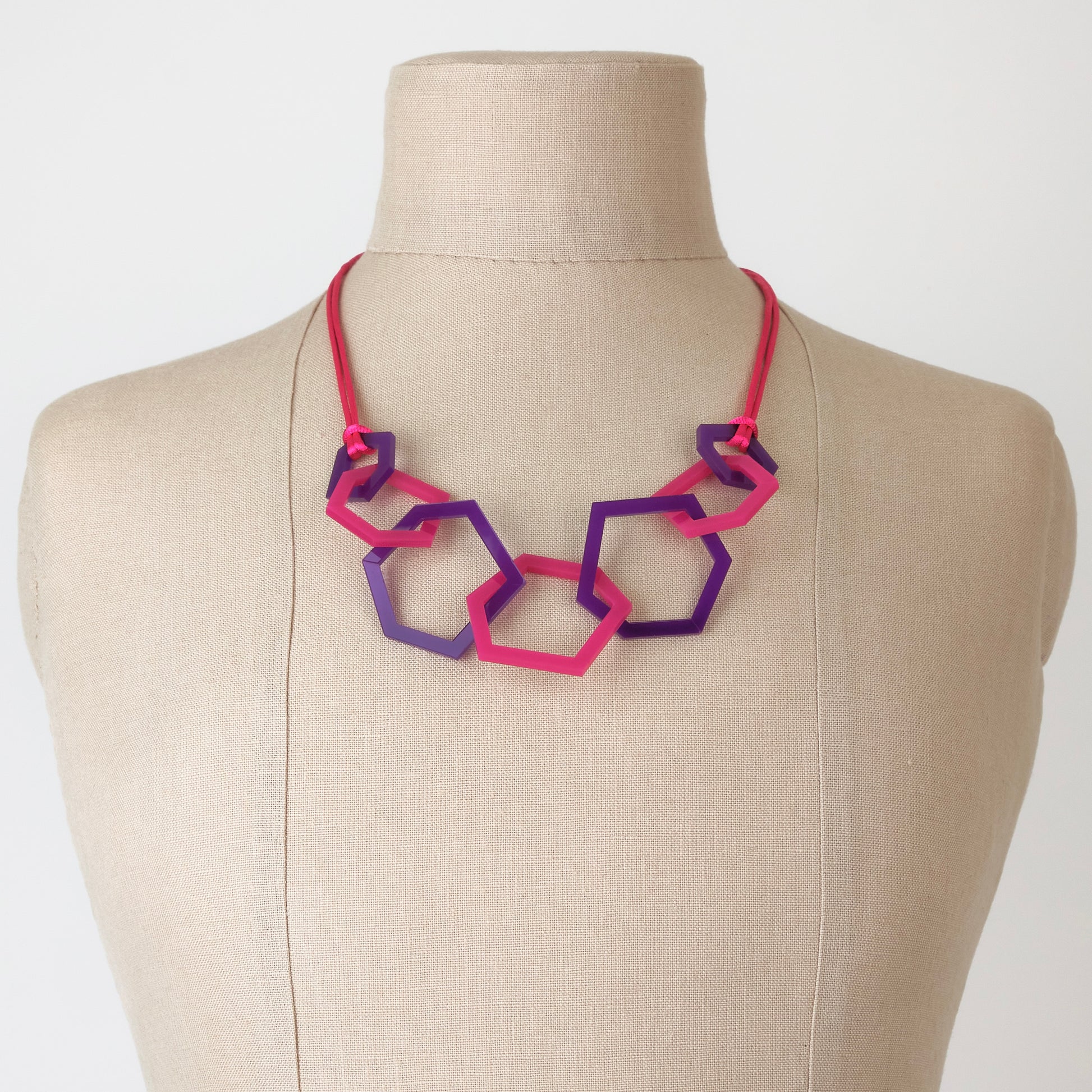 Necklace with pink and purple geometric links on a mannequin bust.