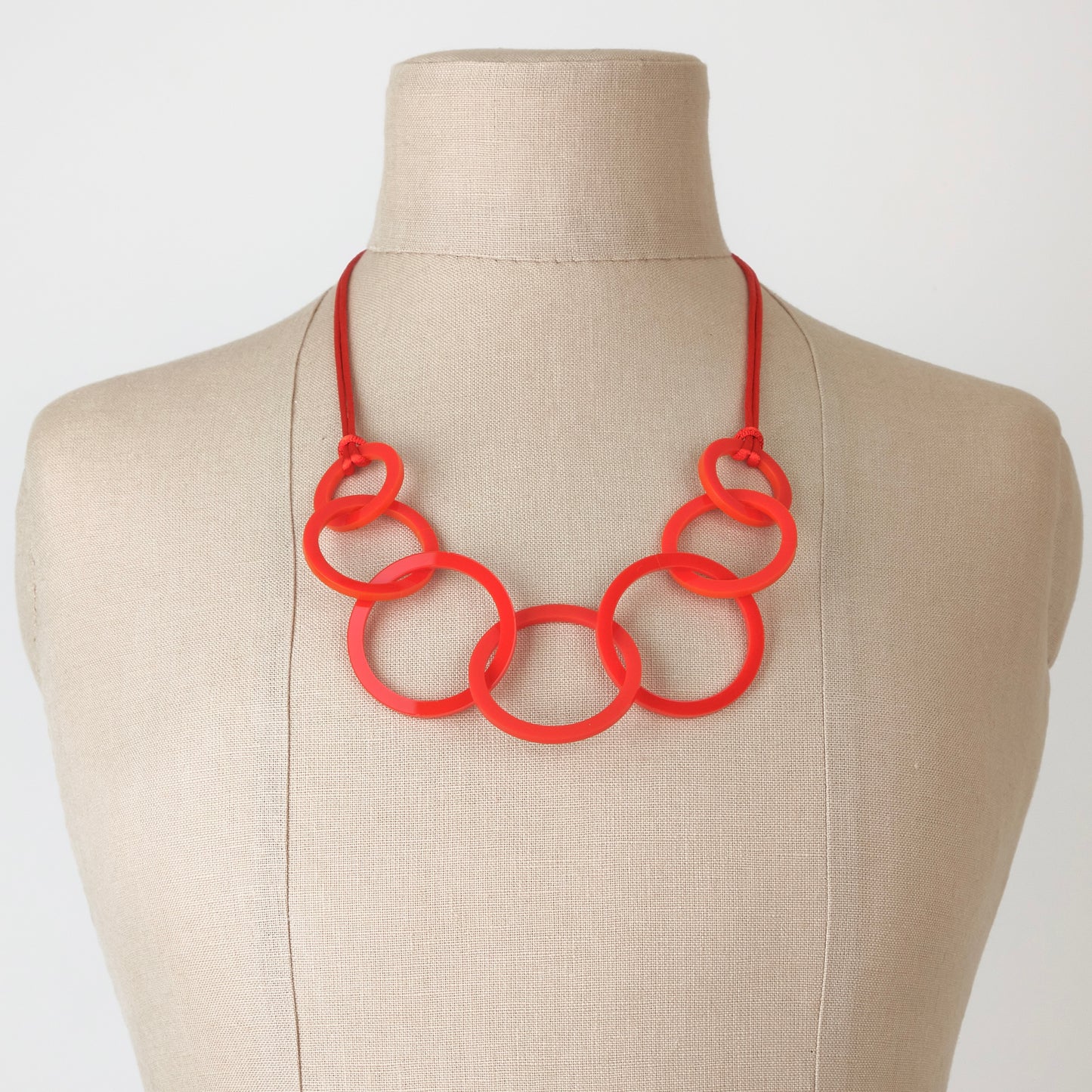 Red circles necklace on a mannequin bust against a plain background