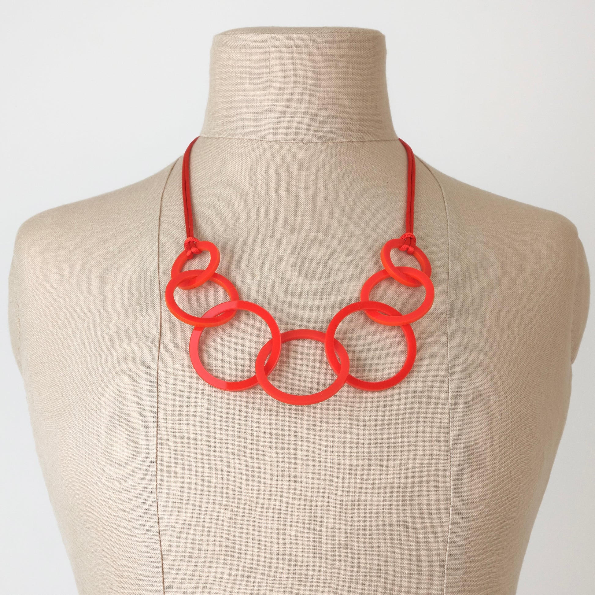 Red circles necklace on a mannequin bust against a plain background