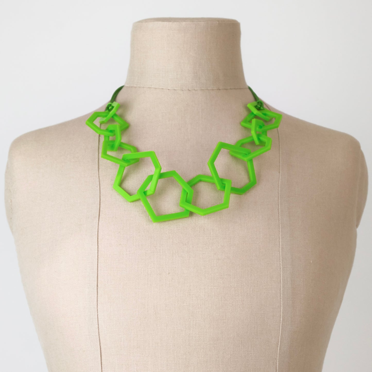 Lime green geometric necklace on a mannequin with a plain background