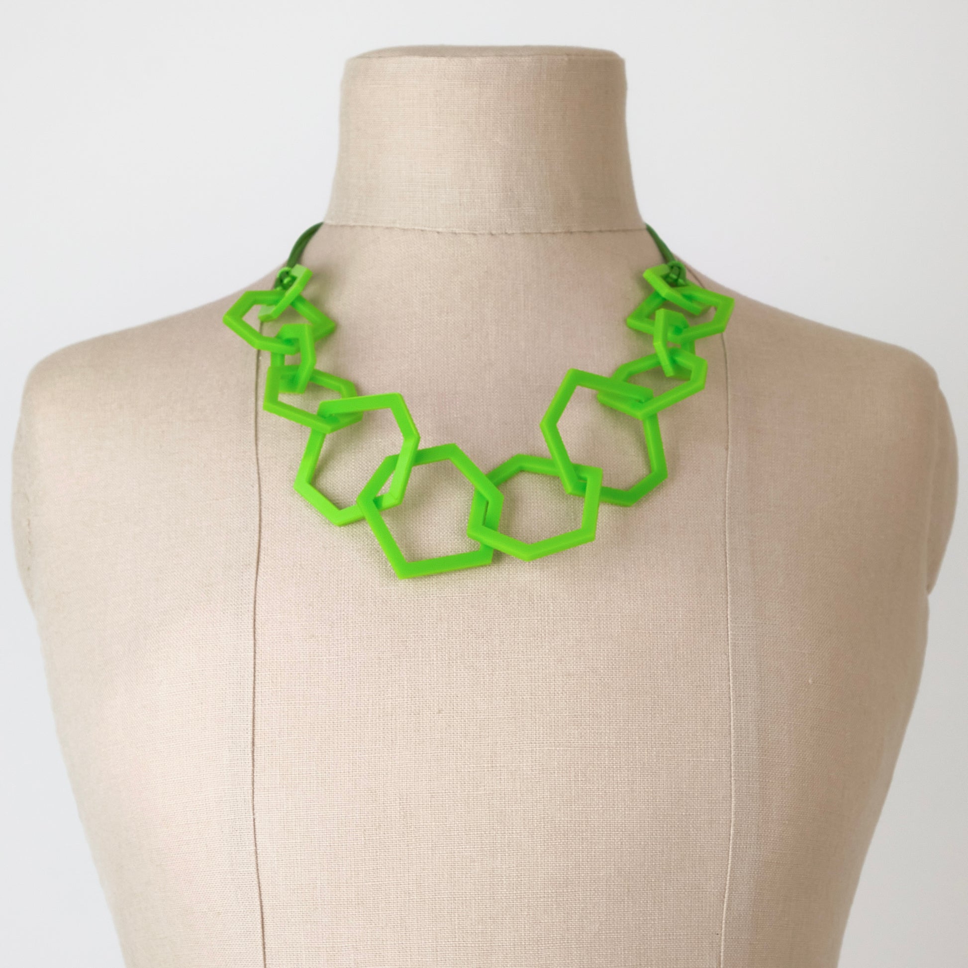 Lime green geometric necklace on a mannequin with a plain background