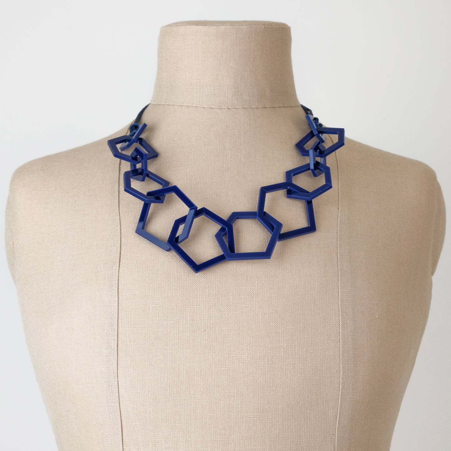 Navy Blue geometric necklace on a mannequin bust against a white background