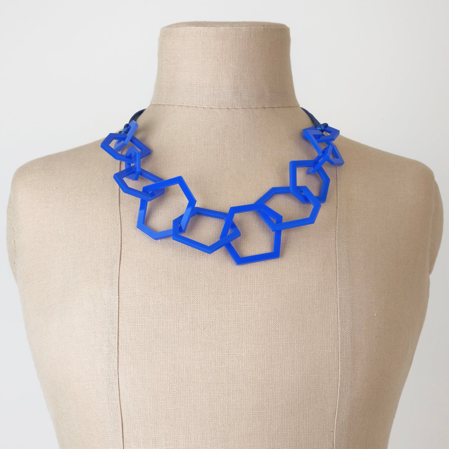 Royal Blue geometric necklace on a mannequin bust against a plain background