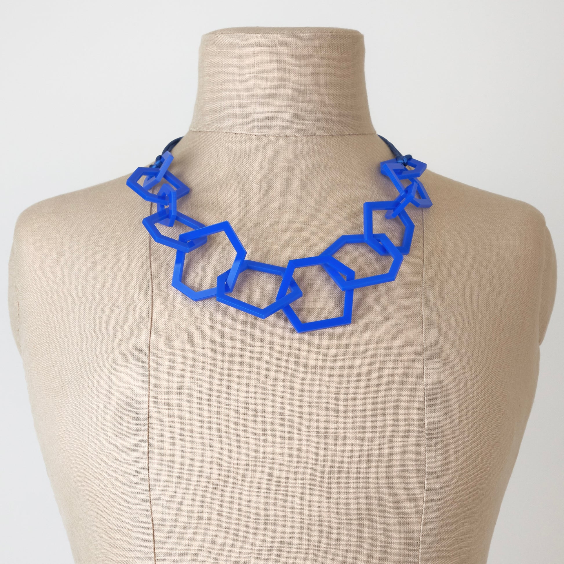 Royal Blue geometric necklace on a mannequin bust against a plain background