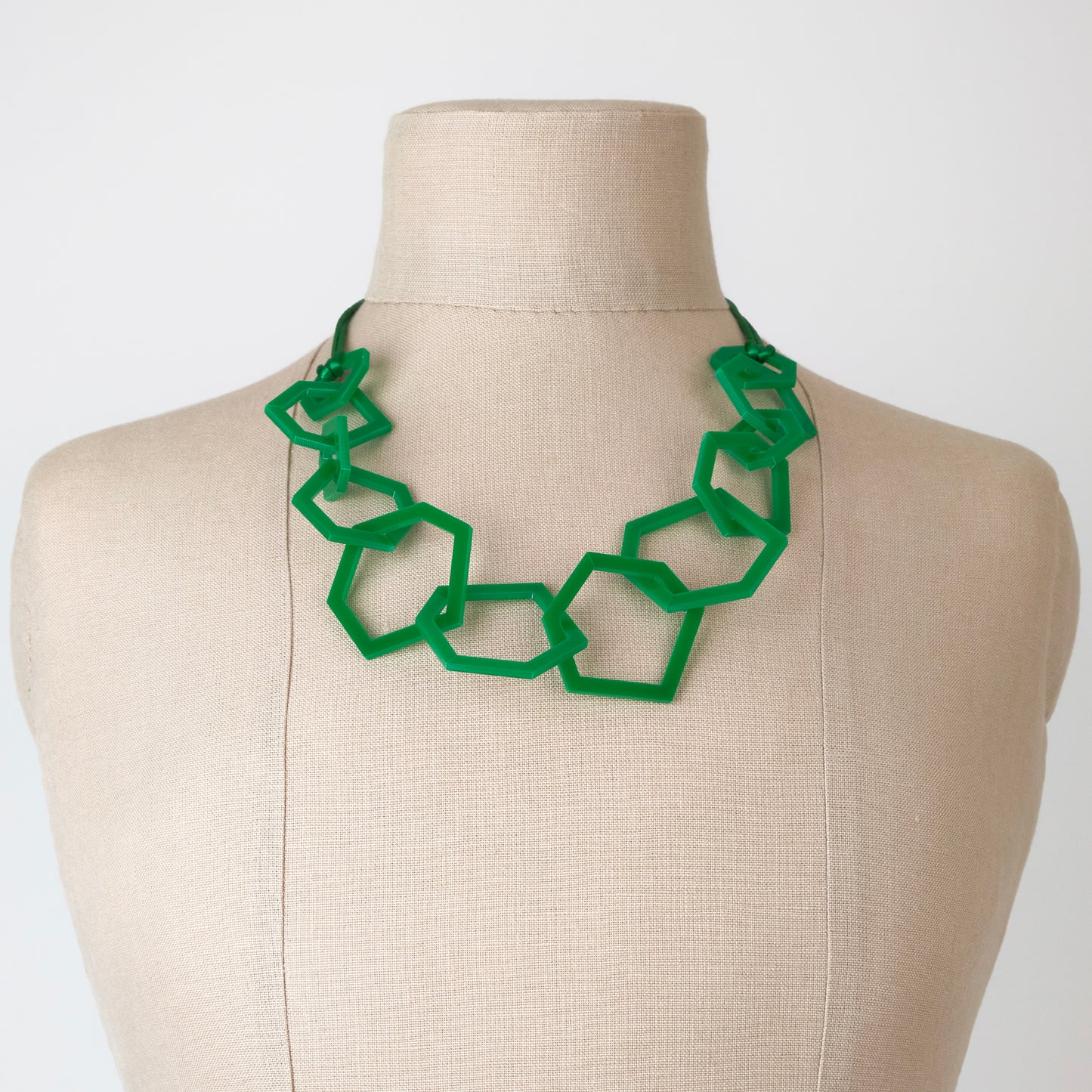 Emerald Green geometric necklace on a mannequin bust against a white background