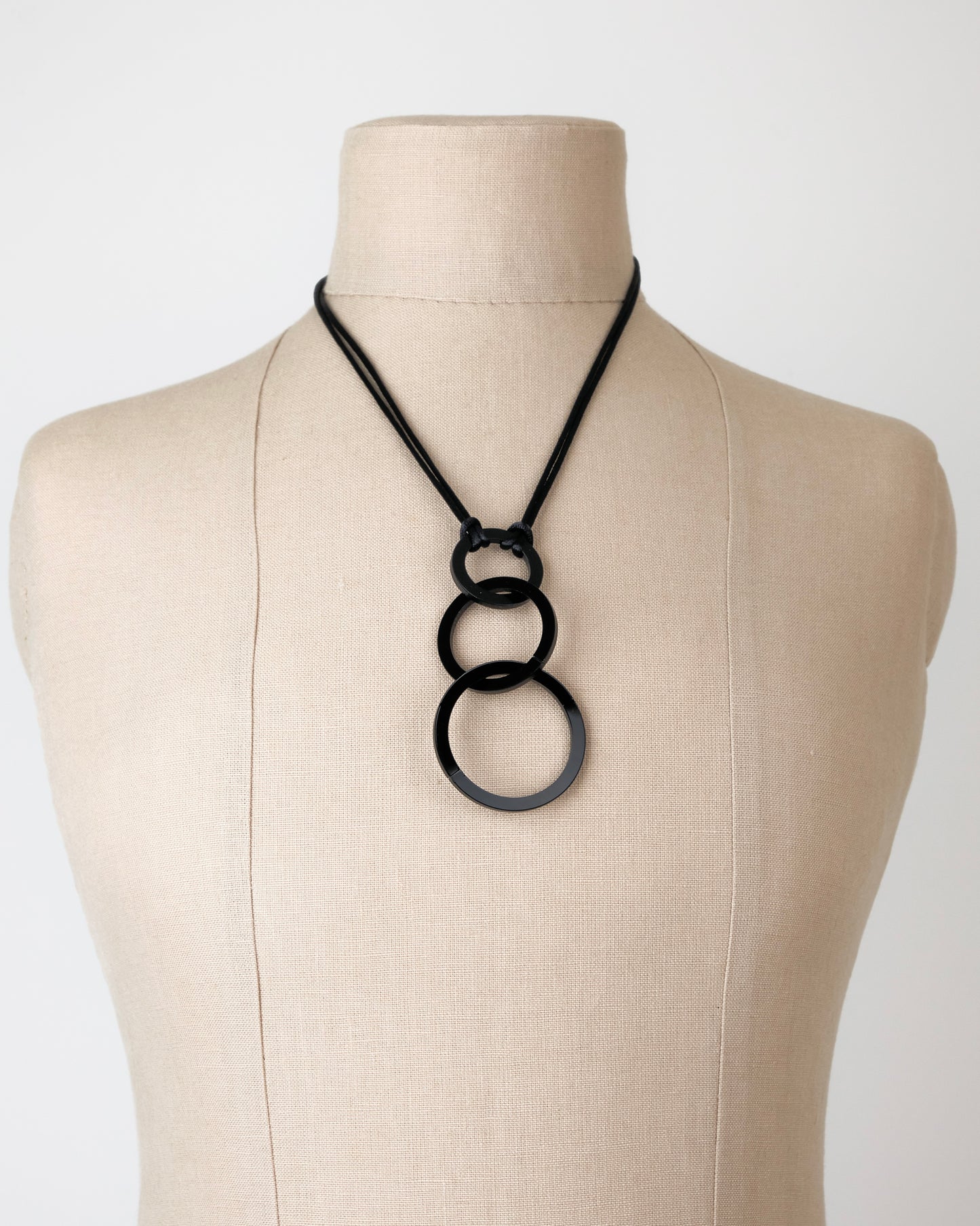Black necklace on a mannequin bust against a white background