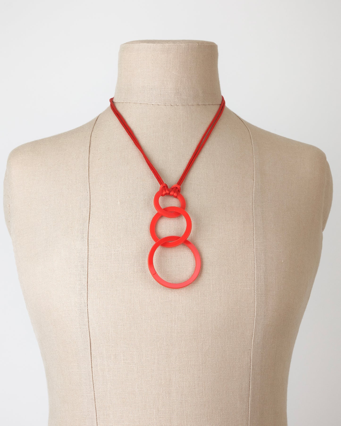 Red necklace on a mannequin bust against a white background